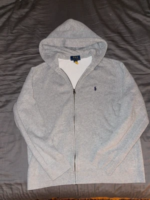  Ralph Lauren - Snygg grå hoodie från Polo Ralph Lauren med dragkedja framtill och klassisk huva. 