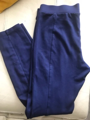 Mörkblå leggings med hög midja - Säljer ett par mörkblå leggings med hög midja och stretchigt material. De har en enkel, stilren design utan synliga loggor eller detaljer. Perfekta för en avslappnad och bekväm look.