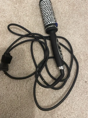 Rundborste - Elektrisk rundborste med svart handtag och vit borste, utrustad med jonteknologi för att minska friss. Borsthuvudet har en diameter på 38 mm och sladden är svart med EU-kontakt. Perfekt för dig som vill ha en fin blowout eller styla håret på annat sett. Använd max 5 gånger.