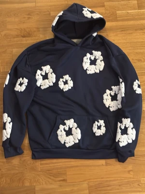 Mörkblå hoodie me blommor - Passar storlek S/M. Har ingen nytta av den. Den är nästan helt ny. Den är blandat material.tunn skulle jag säga. Fraktas direkt efter köp!