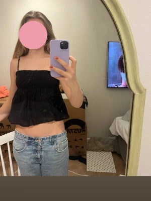 Svart croppad linnetopp - Säljer en svart croppad linnetopp med tunna axelband och rynkad överdel. Bra kvalitet och köpt från Gina tricot. Storlek Xs / Xxs 