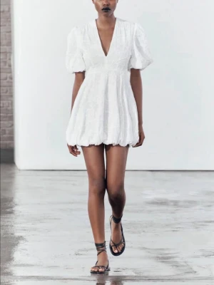 Vit kort klänning med puffärm - Supersöt vit kortklänning med puffärmar och v-ringning. Klänningen har volangkant nertill och ett  broderat mönster i tyget. Perfekt för sommarens alla tillfällen och student!!😇🥂