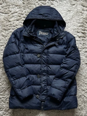 Herno Jacka - Hej, säljer nu min extremt fina och eftertraktade jacka från märket Herno. Jackan kommer med avtagbar luva och foder. Storlek 52 vilket motsvarar M/L. Skriv vid fler funderingar!