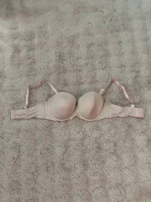 Ljusrosa lättvadderad bh med bygel 85D - Säljer en ljusrosa bh med vadderade kupor och bygel. Bh:n har justerbara/avtagbara axelband och stängs med hyskor i ryggen. Materialet är slätt och ger en enkel, stilren look. Perfekt under ljusa toppar.