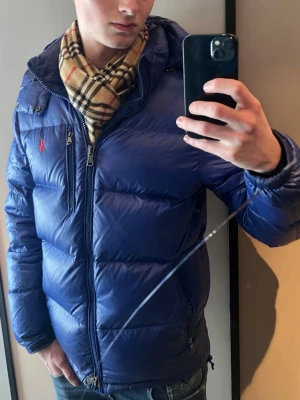 Blå pufferjacka från Polo Ralph Lauren - Marinblå Polo Ralph Lauren pufferjacka, är använd i två säsonger. Är i bra skick! Ny pris för jackan är runt 6 000 kr. Modellen på bilden är 182 cm och väger 70 kg. Skriv bara om du har några frågor! 