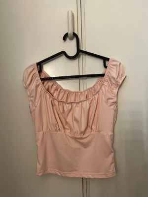 Ljusrosa  topp - Söt ljusrosa topp med korta ärmar och rynkade detaljer. 