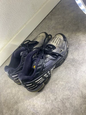 Nike Tuned Air svarta sneakers - Säljer ett par svarta Nike Tuned Air sneakers med vita och grå detaljer. Skorna har en sportig design med synliga luftkuddar i sulan och meshpartier för extra ventilation. Klassisk låg modell med snörning och bekväm vadderad kant.