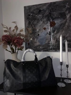 Louis Vuitton svart monogram weekendbag - Säljer en svart weekendbag från Louis Vuitton med klassiskt monogrammönster i mörkgrått. Väskan har dubbla handtag, detaljer i svart läder och en rymlig form som passar perfekt för resor. Snygg och lyxig design som sticker ut.