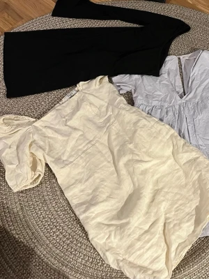 Sommarklänningar - 4st sommarklänningar. ”Fluffig” beige/gul klänning NA-KD strl 38 20kr.  Blå klänning Zara strl S 20kr. Beige tajt klänning Zara strl S (stretchig)  Svart tajt klänning med en arm som är slits typ strl S 20kr.  Paketpris 40kr