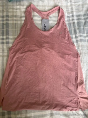 Rosa träningstopp från Calvin Klein - ⚠️Säljer en likadan i XS kika in så du kan matcha med någon⚠️Snygg rosa träningstopp från Calvin Klein med brottarrygg och diskret CK-logga på bröstet. Tillverkad i mjukt och stretchigt material som passar perfekt för gymmet eller löprundan. Enkel och stilren design som ger en sportig look.