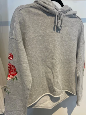 Grå hoodie - En grå hoodie med rosor från H&M, storlek XS.