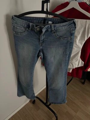 Ljusblå bootcut jeans - Säljer ett par ljusblå bootcut jeans med klassisk femficksdesign och normal midja. Jeansen har en snygg tvättad look och är tillverkade i denim med lite stretch för extra komfort. Perfekta till en avslappnad stil och passar till det mesta.