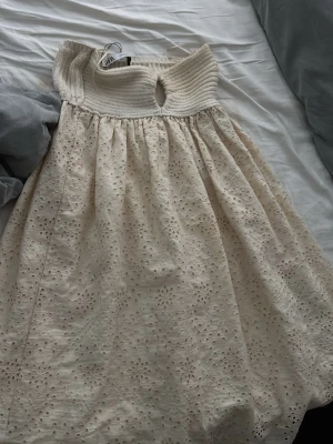Vit spetsklänning från Zara - Söt vit klänning från Zara med ribbad överdel och broderad spets i kjolen. Klänningen har en offshoulder-design och är perfekt för sommarens alla tillfällen. 