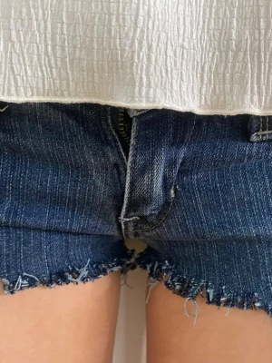 Mörkblåa jeansshorts från Levi's - Säljer ett par mörkblå vintage jeansshorts från Levi's med spets kant🥰aldrig använda, endast testade💕de är i storlek 26 passar xs. Pris kan diskuteras 🥰