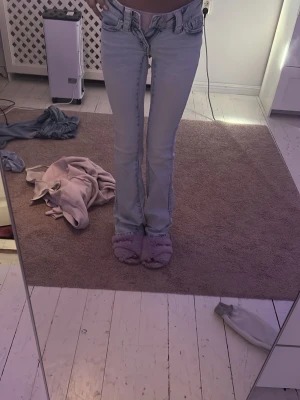 Ljusblå bootcut jeans  - Säljer ett par ljusblå bootcut jeans från ginatricot med klassiska fickor och broderad W-detalj bak. Jeansen har låg midja och utsvängda ben