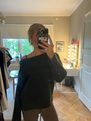 Mörkgrön off shoulder stickad tröja från Gina - Mysig mörkgrön stickad tröja med avslappnad passform och off shoulder-design. Tröjan har långa ärmar och är tillverkad i ett mjukt, fluffigt material som ger en chill vibe. Perfekt för lager på lager och passar till både jeans och mjukisbyxor. Passar som xs 
