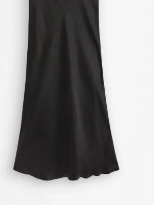 Svart långkjol i satin - Stilren svart långkjol i glansigt satinmaterial med lätt utsvängd passform. Kjolen har en enkel och elegant design utan synliga detaljer eller mönster, vilket gör den lätt att matcha med olika toppar. Perfekt för dig som gillar en klassisk och trendig look.