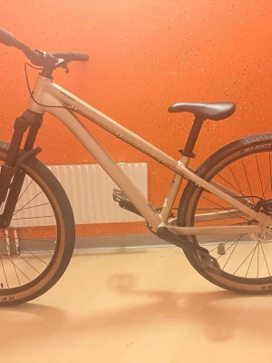 Kiez dirtbike beige med svart - Säljer en beige dirtbike från Kiez med svart sadel, svarta hjul och detaljer. Cykeln har robust ram, grova däck och raka styren, perfekt för tricks och streetriding. Pedaler och kedjeskydd i metall, samt tydlig logga på ramen.