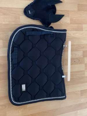 Marinblått schabrak & huva till häst - Säljer ett marinblått schabrak med matchande huva från Equestrian Stockholm. Schabraket har quiltat mönster, vita och silverfärgade detaljer längs kanten och kardborrefästen. Huvan nästan aldrig använt och shabraket i bra skick, inget upp rivet eller nått sånt. Storlek full