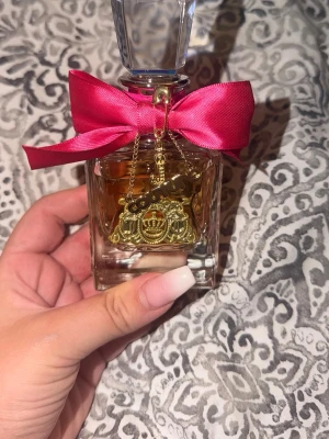 Juicy Couture parfym viva la juicy - Juicy Couture parfymflaska Flaskan har en elegant, kristalliknande kork och detaljer i guld. Perfekt för dig som gillar lyxiga och söta dofter. 50ml