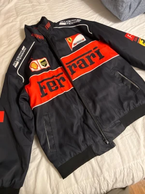 Ferrari jacka - 🏎️ Ferrari Scuderia Racing Jacka – Storlek M  Säljer en riktigt snygg Ferrari Scuderia Racing-jacka i storlek M. Jackan är i mycket fint skick och har den klassiska Ferrari-designen med broderade loggor och detaljer som verkligen sticker ut.  ✨ Information: • Storlek: M • Mycket fint skick • Dragkedja framtill • Broderade Ferrari- och sponsorloggor • Bekväm passform • Svart/röd design  📦 skickas snabbt 