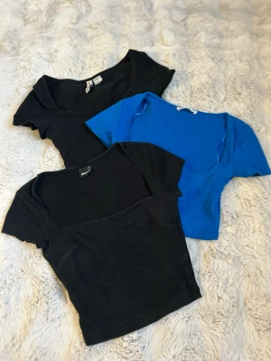 Svarta och blå croppade toppar Gina Tricot, H&M och Zara - Tre croppade toppar från Gina Tricot, H&M och Zara i svart och blått. Alla har korta ärmar och fyrkantig ringning. Säljer alla tre  tillsammans.