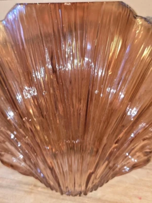 Brun snäckformad vas - Säljer en snygg snäckformad vas i  glas. Skålen har räfflad yta och unik form som påminner om en snäcka, perfekt som dekoration eller för snacks. Materialet är glas och färgen peach. Höjd 21 cm