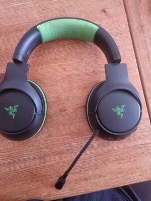 Razer gaming headset med mikrofon - Snyggt gaming headset från Razer i svart och grönt med stora, mjuka öronkuddar och justerbart huvudband. Headsetet har en flexibel mikrofon och tydlig Razer-logga på kåporna. Perfekt för långa spelsessioner och bra ljudupplevelse.