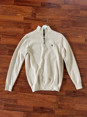 Beige Polo RL half-zip - Snygg vintage beige RL half-zip med hög krage. Tröjan är endast använd ett fåtal gånger. Storleken är M och passar dig mellan 175 till 185 cm. Jag är 182 cm och den passar mig bra. Säljes pga brist av användning. Det är bara att höra av sig vid frågor!