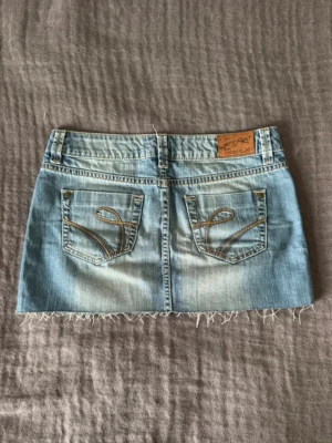 Ljusa jeanskjol från Esprit - Cool ljusblå jeanskjol från Esprit med fransig nederkant och låg midja. Kjolen har snygga broderade detaljer på bakfickorna och en skön passform.