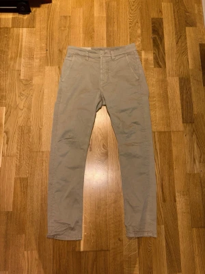 Beige chinos med raka ben 28L 28W, modell Slim Adam - Snygga beige chinos med raka ben och klassisk passform. 28L 28W Perfekta för en clean och stilren look. Materialet känns mjukt och bekvämt.