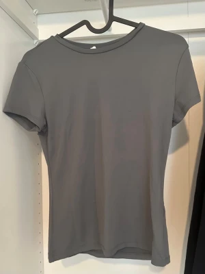 Grå basic t-shirt - En enkel och stilren grå t-shirt med rund hals och korta ärmar. Perfekt för dig som gillar minimalistisk stil. T-shirten har en normal passform och är tillverkad i mjukt material som känns skönt mot huden.