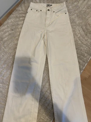 Vida vita jeans från 157 - Säljer ett par vita jeans från 157 med hög midja och raka, vida ben. Klassisk femficksmodell med knapp- och dragkedjegylf. Perfekta för en clean och stilren look. Materialet är bomull som känns mjukt och bekvämt.