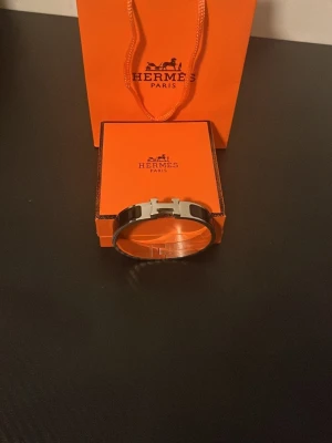 H svart Clic H armband - Snyggt svart H Clic H armband i emalj och silverfärgad metall. Armbandet har den ikoniska H-detaljen framtill och kommer i originalask och påse. Perfekt accessoar för dig som gillar exklusiv och stilren design.