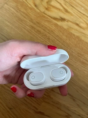 Vita trådlösa in-ear hörlurar - Säljer ett par stilrena vita trådlösa in-ear hörlurar med laddningsetui. Hörlurarna har en minimalistisk design med rundade kanter och diskreta knappar på ovansidan. Perfekta för musik, poddar eller samtal på språng. Jag har inte testat de då jag fick de i present och vet ej hur de funkar 