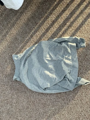 Grå hoodie från ASOS DESIGN - En enkel och stilren grå hoodie från ASOS DESIGN. Hoodien har en klassisk huva och dragkedja framtill. Tillverkad i mjukt sweatshirtmaterial som är skönt mot huden. Perfekt för en avslappnad look och funkar året runt.