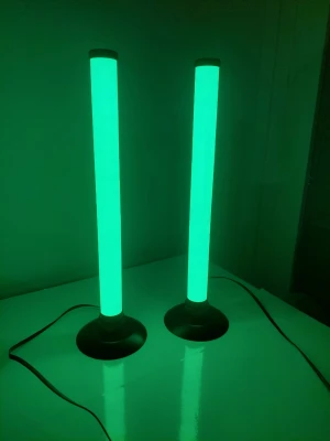 Två LED RGB-ljusrör med svart fot - Säljer två cylinderformade LED-ljusrör med svart rund fot. Lamporna kan skifta färg mellan grönt och vitt/blått och har en modern, minimalistisk design. Perfekt för gaminghörnan eller som cool dekoration i rummet. Strömkabeln är svart och lamporna är tillverkade i plast och metall.