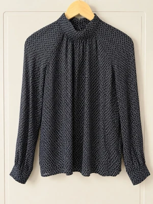Mönstrad blus från Second Female - Snygg svart blus från Second Female med vitt grafiskt mönster. Hög krage med knappar i nacken och långa ärmar. Tillverkad i 100% viskos vilket ger ett mjukt och följsamt fall. Perfekt till jeans eller kjol för en trendig look.