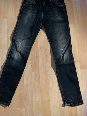 Replay anbass jeans - Säljer ett par mörka blåa replay jeans med slitningar på knäna och lätt tvättad look. Jeansen har raka ben och klassisk femficksmodell. Materialet är denim och de har kontrastsömmar. Perfekta för en avslappnad streetstil.