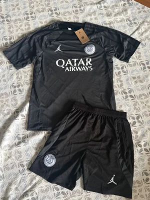 Svart PSG träningsset Jordan - Jordan x Paris Saint-Germain fotbollsset i storlek M. Shortsen har fickor med dragkedjor. Helt nya och oanvända, perfekt till sommaren. Hör gärna av vid frågor!