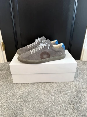 Oliver Cabell Low 1 Pigment - Snygga gråa sneakers från Oliver Cabell i en ljusgrå färg med deras klassiska runda logga i färgen blå. Skorna är använda max 10 gånger och pruta är helt okej.