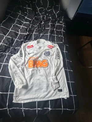 Santos FC Neymar Jr #11 Matchtröja Långärmad – Strl M – Äkta & Helt Ny - Säljer en äkta Santos FC Neymar Jr #11 långärmad matchtröja i storlek M. Tröjan är helt ny och oanvänd, i perfekt skick. Den ikoniska vita designen med klassiska sponsorer och Neymar Jr:s namn samt nummer 11 på ryggen gör den till ett måste för både samlare och fotbollsfans.  ✔️ Lag: Santos FC ✔️ Spelare: Neymar Jr #11 ✔️ Storlek: M ✔️ Skick: Helt ny och oanvänd ✔️ 100 % autentisk ✔️ Färg: Vit ✔️ Långärmad modell ✔️ Nike Dri-FIT-material för hög komfort ✔️ Perfekt för samlare, fans och matchdagar 