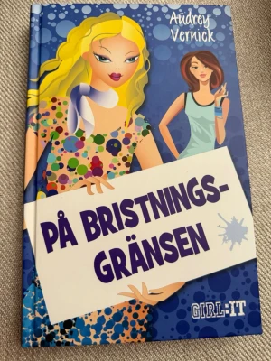 På bristningsgränsen av Audrey Vernick - Ungdomsroman med färgglad hård pärm, blå bakgrund och illustrationer av två tjejer. Boken handlar om Marley och hennes livsförändringar, vänskap och familj. Perfekt för dig som gillar lättlästa och roliga berättelser om tonårsliv.