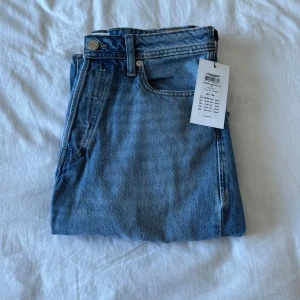 Oanvända blå jeans med slitna knän från Jack & Jones  - Säljer ett par blå jeans från Jack & Jones med raka ben och slitna detaljer över båda knäna. Klassisk femficksmodell i bomullsjeans med normal passform och dragkedja. Oanvända med tags kvar. (Nypris 499)