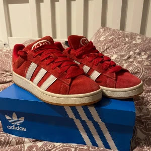 Adidas Campus röda sneakers strl 46 - Säljer ett par Adidas Campus sneakers i rött mocka med klassiska vita ränder på sidorna och vit sula. Skorna har rund tå, platt sula och snörning. Perfekt för dig som gillar retrostil och vill sticka ut med färg. Storlek 46 (US 11,5).(använda cirka 3 gånger)
