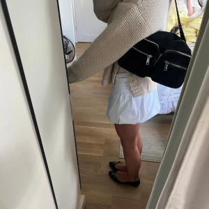 Svart axelväska med nitar och dragkedjor - Cool svart axelväska i manchester med två stora framfickor och silvriga dragkedjor. Axelremmen är dekorerad med silvriga nitar som ger en edgy vibe. Perfekt storlek för att få plats med allt du behöver och passar till många olika outfits. Inga defekter och använd ett fåtal gånger. 