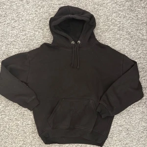 Hoodie - Svart hoodie från BikBok i storlek XS. Klassisk modell med huva och snörning, samt en stor magficka framtill. Mjuk insida och ribbade muddar vid ärmslut och nederkant. Perfekt för chill dagar eller när du vill ha en enkel och clean look.