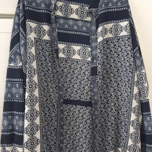 Klänning - Säljer en snygg klänning från Boohoo i storlek 36. Klänningen har ett unikt blåvitt mönster med blommiga och geometriska detaljer, långärmad och med avslappnad passform. Perfekt för dig som gillar boho-vibes och vill sticka ut med coola prints.