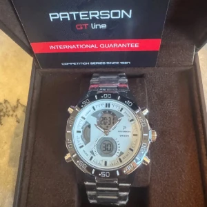Paterson GT Line silverklocka - Oanvänd stilren Paterson GT Line herrklocka i rostfritt stål med silverfärgad länk och vit urtavla. Klockan har både analog och digital display, svart vridring och flera knappar för funktioner som kronograf och dual time. Perfekt accessoar för dig som gillar sportig och modern stil.