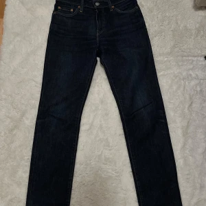 Levi's 511 mörkblå jeans W30 L32 - Säljer ett par Levi's Premium 511 jeans i mörkblå tvätt. Modellen är slim och har klassisk femficksdesign med snygga kontrastsömmar. Jeansen är tillverkade i slitstarkt denim och har en modern, rak passform som sitter snyggt på benen.